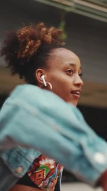 Kapalı çekim, at kuyruklu gülümseyen Afrikalı kız, at kuyruğu ceketli, tarlada milli şablon ile kulaklıkla müzik dinliyor ve açık havada dans ediyor. Yavaş çekim