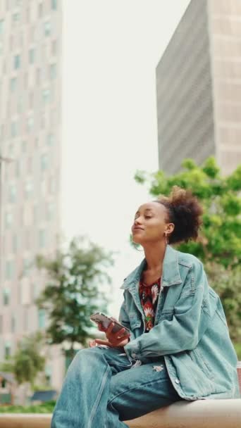 Vertical Video Nettes Afrikanisches Mädchen Mit Pferdeschwanz Jeansjacke Sitzt Und — Stockvideo