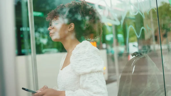Gözlüklü Genç Bir Kadın Otobüs Durağında Dikilirken Akıllı Telefona Bakıyor — Stok fotoğraf