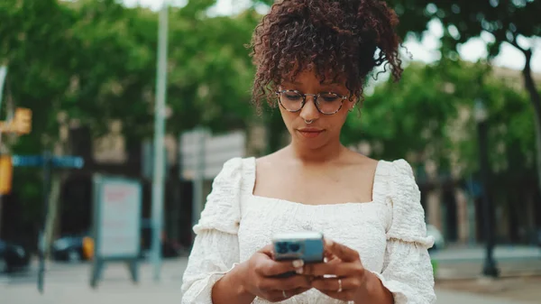 Gözlüklü Genç Bir Kadın Elinde Akıllı Telefonuyla Ayakta Duruyor Etrafına — Stok fotoğraf