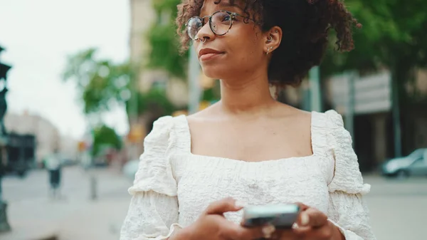 Gözlüklü Genç Bir Kadın Elinde Akıllı Telefonuyla Ayakta Duruyor Etrafına — Stok fotoğraf