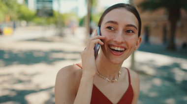 Şirin genç bir bayan sokakta cep telefonu kullanıyor. Kız eski şehrin arka planında bir bankta oturuyor ve akıllı bir telefonla konuşuyor.