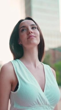 Çilli, koyu renk saçlı, beyaz bluzlu, gülümseyen genç bir kadın caddeden aşağı iniyor. Uzun kirpikleri olan güzel bir kız modern şehrin caddelerinde yürüyor.