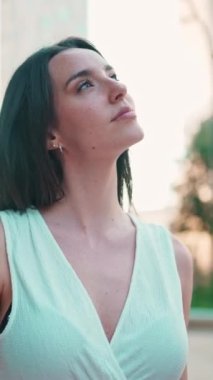 Çilli, koyu renk saçlı, beyaz bluzlu ve kot pantolonlu hoş bir genç kadın caddeden aşağı iniyor. Uzun kirpikleri olan güzel bir kız modern şehrin caddelerinde yürüyor.