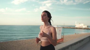 Saçı örülü, bej rengi spor giyinen genç atletik bir kadın.