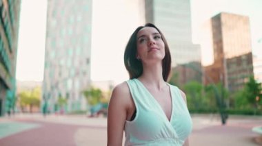 Çilli, koyu renk saçlı, beyaz bluzlu ve kot pantolonlu gülümseyen genç bir kadın caddeden aşağı iniyor. Uzun kirpikleri olan güzel bir kız modern şehrin caddelerinde yürüyor.