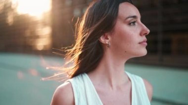 Çilli, koyu renk saçlı, beyaz bluzlu ve kot pantolonlu güzel bir kadın yüzünü kameraya çeviriyor. Modern şehir geçmişinde güzel bir kız.