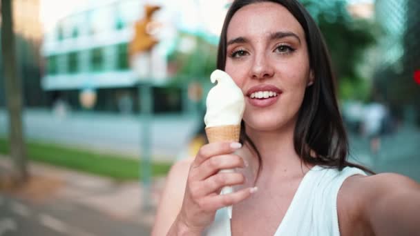 由身穿白色上衣 长着雀斑和深色蓬松头发的美女组成的特写镜头正在测试冰淇淋和自拍 可爱的女孩喜欢现代都市背景的冰淇淋 — 图库视频影像