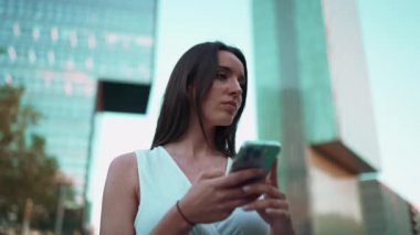 Çilli, siyah saçlı, beyaz bluzlu güzel bir kadın cep telefonundan haritaya bakıyor. Güzel kız yerini belirlemek için akıllı telefon kullanıyor.