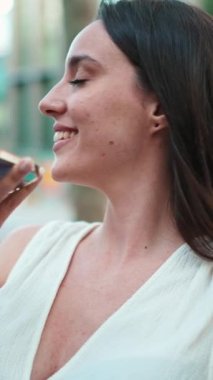 Çilli, koyu renk saçlı, beyaz bluzlu güzel bir kadın elinde telefonuyla bankta oturuyor. Hoş bir kız cep telefonundan sesli mesaj gönderiyor. Modern şehir geçmişi.