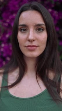 Çilli, koyu renk saçlı, beyaz bluzlu güzel bir kadın bankta oturur ve etrafına bakar. Şirin kız modern şehir geçmişinde oturuyor.