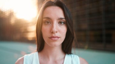 Çilli, koyu renk saçlı, uzun kirpikli, beyaz bluzlu ve kameraya bakan genç bir kadının yakın plan portresi. Modern şehir geçmişinde güzel bir kız.