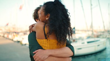 Yakın plan, ırklar arası genç çiftin mutlu buluşması. Genç bir erkek ve kadın, yat arka planındaki sette buluştuklarında sevinçle kucaklaşırlar. Kamera insanların etrafında döner