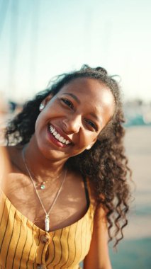 Yatın arka planında uzun kıvırcık saçlı, gülümseyen kızın yakın plan portresi. Cep telefonu kullanan mutlu genç bir kadının önden yakın çekimi.