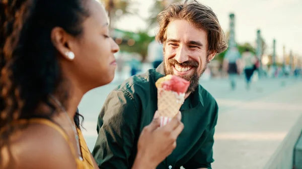 幸せな異人種間のカップル都市の背景にアイスクリームを食べるのクローズアップ肖像画 男と女の試飲アイスクリームのクローズアップ バックライト — ストック写真