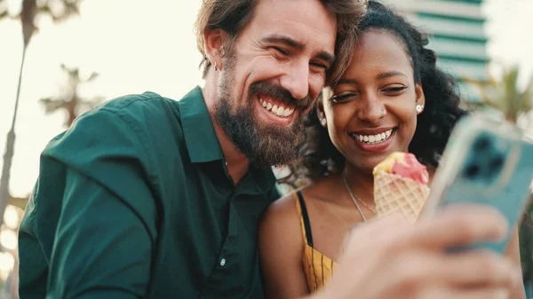 スマートフォンでビデオを見ている幸せな男と笑顔の女性の肖像画 都市の背景に携帯電話で楽しい若い異人種間カップルのブラウジング写真のクローズアップ — ストック写真