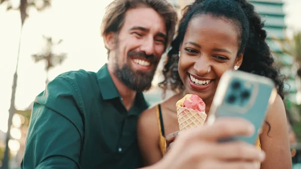 スマートフォンでビデオを見ている幸せな男と笑顔の女性の肖像画 都市の背景に携帯電話で楽しい若い異人種間カップルのブラウジング写真のクローズアップ — ストック写真
