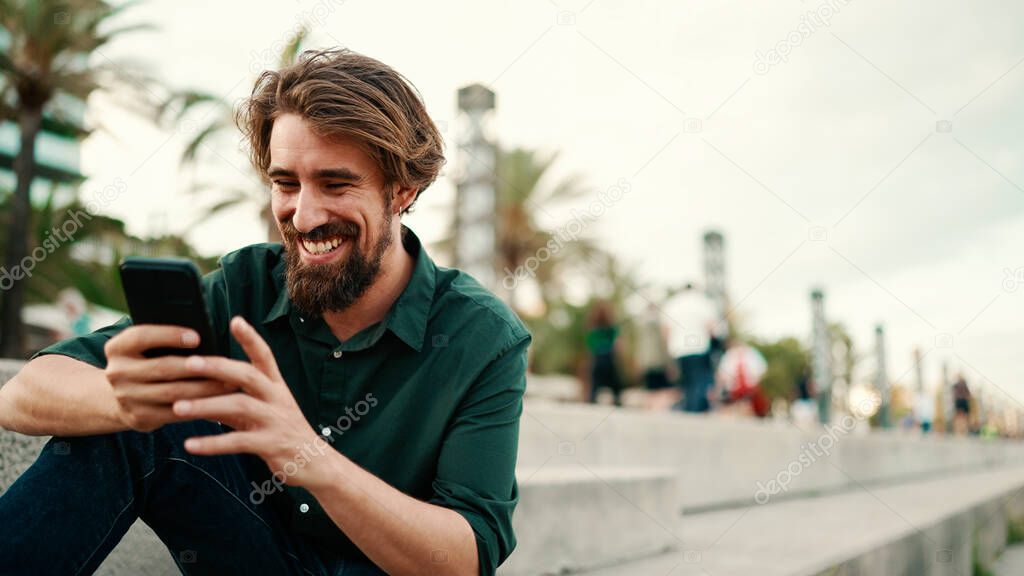 Close-up portrait of a man with a beard recording a voice message on the embankment background. Closeup of a young hipster male using a mobile phone