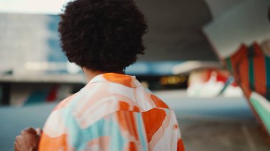 Tişört giyen, kulaklıkla müzik dinleyen ve şehir arka planında dans eden neşeli genç Afrikalı Amerikalı adamın yakın çekimi. Yaşam tarzı kavramı. 