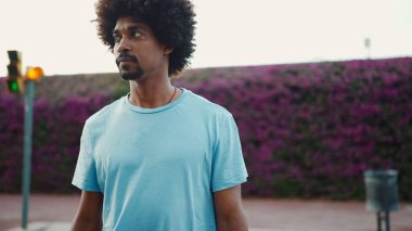 Arkadaki duvarda mor çiçeklerle kaplı şehir sokağına çıkan genç bir Afro-Amerikalı. Yaşam tarzı kavramı