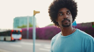 Arkadaki duvarda mor çiçeklerle kaplı şehir sokağına çıkan genç bir Afro-Amerikalı. Yaşam tarzı kavramı