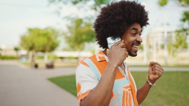 Parktaki yolda yürürken ve akıllı telefondan konuşan Afro-Amerikan genç adamın yakın çekimi. Cep telefonuyla duygusal konuşan bir adam. Yaşam tarzı kavramı. 