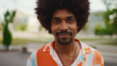Kameraya bakıp gülümseyen, gömlek giyen Afro-Amerikan genç bir adamın yakın plan portresi. Kamera şahsa doğru ilerliyor. Yaşam tarzı kavramı. 
