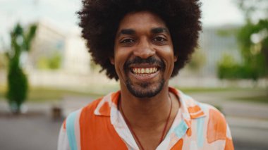 Kameraya bakıp gülümseyen, gömlek giyen Afro-Amerikan genç bir adamın yakın plan portresi. Kamera şahsa doğru ilerliyor. Yaşam tarzı kavramı. 