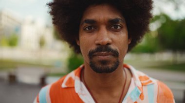 Kameraya bakıp gülümseyen, gömlek giyen Afro-Amerikan genç bir adamın yakın plan portresi. Kamera şahsa doğru ilerliyor. Yaşam tarzı kavramı. 