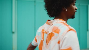 Açık mavi duvar arka planında kameraya gülümseyen, gömlekli, neşeli, Afro-Amerikan bir adamın yakın plan portresi. Yaşam tarzı kavramı. 