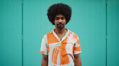 Açık mavi duvar arka planında kameraya gülümseyen, gömlekli, neşeli, Afro-Amerikan bir adamın yakın plan portresi. Yaşam tarzı kavramı. 