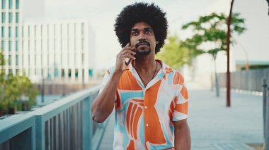 Gömlek giyen ve akıllı telefondan konuşan Afrikalı genç bir adamın yakın çekimi. Yaşam tarzı konsepti. Yavaş çekim geri aydınlatma. 