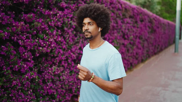 Kapalı kapılar ardında mor çiçeklerle kaplı, kablosuz kulaklıkla müzik dinleyen ve dans eden genç, Afro-Amerikan bir adam. Yaşam tarzı kavramı.