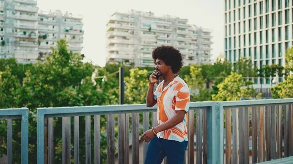 Gömlek giyen ve akıllı telefondan konuşan Afrikalı genç bir adamın yakın çekimi. Yaşam tarzı konsepti. Yavaş çekim geri aydınlatma. 