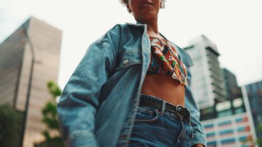 Yakından, at kuyruklu, kot ceketli, milli modelli giyinmiş kulaklıkla müzik dinleyen ve dışarıda dans eden Afrikalı kız.. 