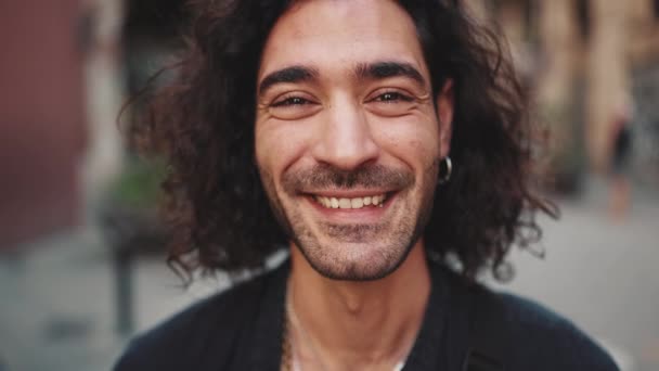 머리가 곱슬곱슬 매력적 이탈리아 청년의 카메라를 들여다보며 배경에 미소를 귀고리가 — 비디오