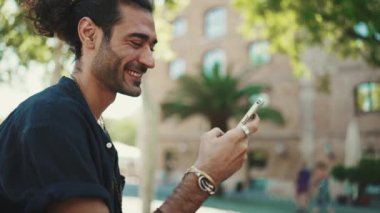 At kuyruklu ve sakallı çekici İtalyan adam eski binaların arkasındaki bankta oturan cep telefonunu kullanıyor. Tarz sahibi bir adam mesaj yazar, akıllı telefondan fotoğrafa bakar