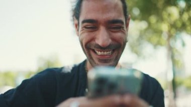 Gülümseyen at kuyruklu ve sakallı çekici İtalyan adamın yakın çekimi eski binaların arka planında otururken cep telefonu kullanıyor. Tarz sahibi adam mesaj yazar, fotoğrafa telefonla bakar.