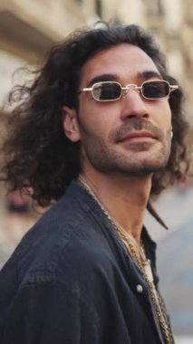 Uzun kıvırcık saçlı ve sakallı genç İtalyan adam yaya geçidi boyunca yürüyor. Güneş gözlüklü, zincirli şık bir adam karşıdan karşıya geçer ve etrafa bakar.