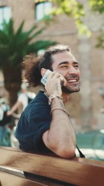 At kuyruklu ve sakallı çekici İtalyan adam eski binaların arkasındaki bankta otururken cep telefonu kullanıyor. Şık bir adam, duygusal olarak akıllı telefondan konuşuyor.