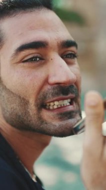 Clouse-up, at kuyruklu ve sakallı çekici İtalyan adam eski binaların arkasındaki bankta cep telefonu kullanıyor. Tarz sahibi adam akıllı telefondan sesli mesaj gönderiyor.