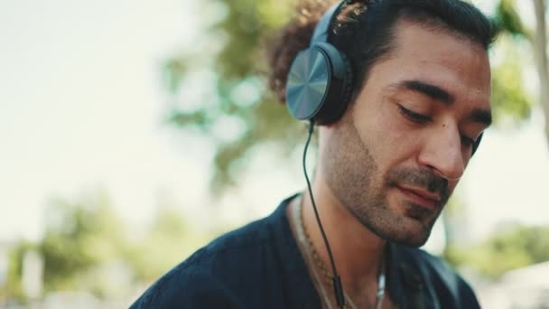 포니테일 머리를 길거리 벤치에 헤드폰을 음악을 이탈리아 청년의 — 비디오