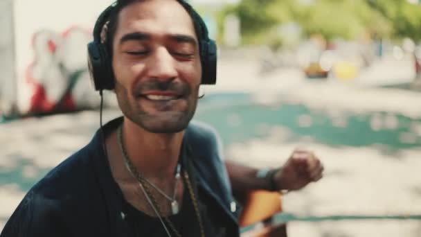 머리에 포니테일 머리를 길거리 벤치에 헤드폰을 음악을 이탈리아 청년의 — 비디오