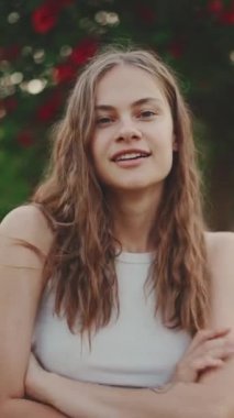 Koyu sarı dalgalı saçlı, gülümseyen güzel bir kızın yakın çekimi. Güzel kız kameraya gülümsüyor.