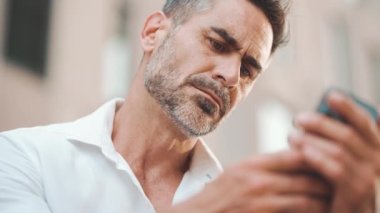 Sakallı, olgun bir iş adamı cep telefonu kullanıyor şehrin finans bölgesinde bankta oturuyor. Adam akıllı telefondan bilgi aktarıyor. Kamera yakınlaştır
