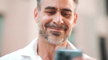 Sakallı, olgun bir iş adamı şehrin finans bölgesinde cep telefonu kullanıyor. Adam akıllı telefon ve gülücüklerle bilgi topluyor. Kamera hareket ediyor