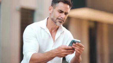 Sakallı, olgun bir iş adamı şehrin finans bölgesinde bankta cep telefonu kullanıyor. Başarılı adam akıllı telefondan bilgi aktarıyor. Kamera yakınlaştır