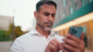 Sakallı, olgun iş adamı cep telefonu kullanıyor. Başarılı bir adam akıllı telefondan mesaj göndererek bilgileri aktarır.