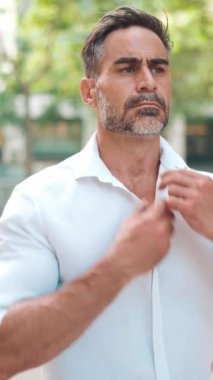 Tıknaz, sakallı, olgun bir iş adamı beyaz gömleğini düzeltiyor, modern şehrin sokaklarında yürüyor. Başarılı adam rahat, hayattan zevk alıyor.