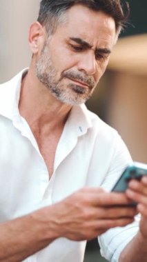 Sakallı, olgun bir iş adamı cep telefonu kullanıyor şehrin finans bölgesinde bankta oturuyor. Başarılı adam akıllı telefondan bilgi aktarıyor.